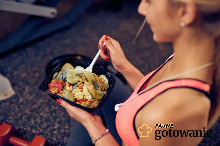 Kobieta w stroju treningowym jedząca posiłek, a także diety treningowe oraz ich zasady i jadłospis
