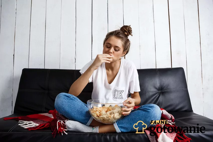 Comfort food - czy jest wrogiem podczas odchudzania? Kobieta jedząca chipsy na kanapie.