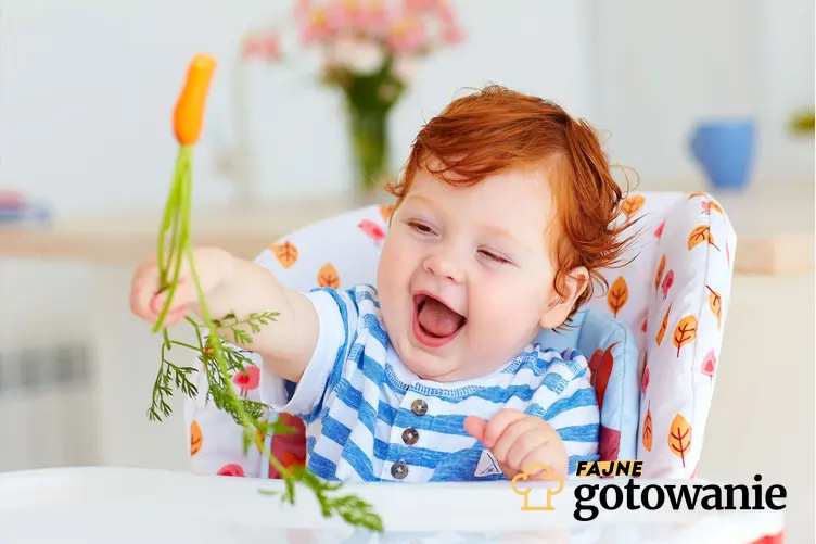 Dziecko siedi w krzesełku do karmienia i w ręce trzyma marchewkę z natką, śmieje się, a także informacje na temat zagrożeń wynikających z jedzenia pewnych produktów przez małe dzieci.