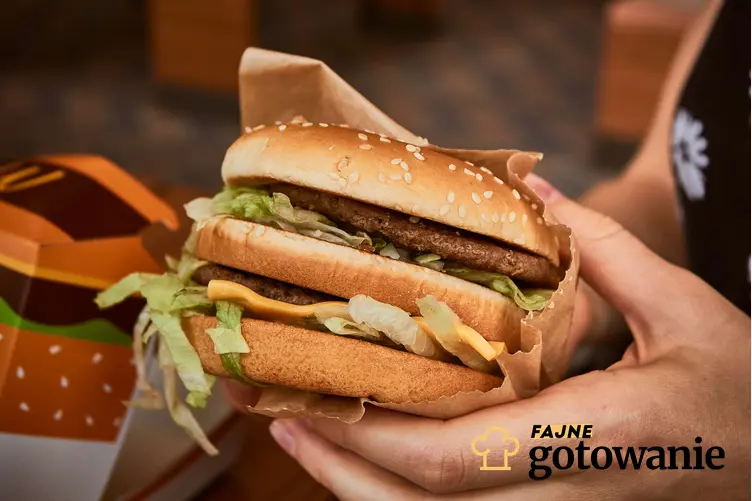 Osoba trzyma hamburgera w dłoniach, a także jedząc fast foody można schudnąć
