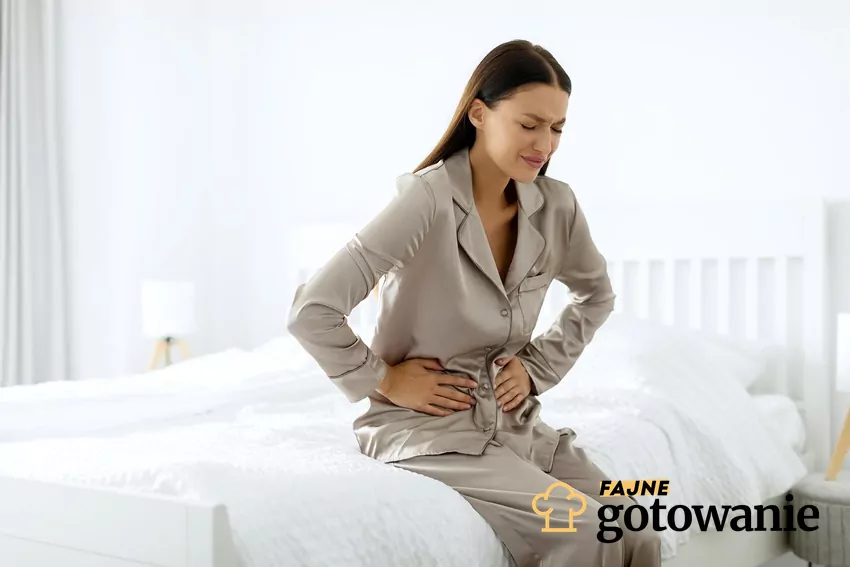 Kobieta siedzi i trzyma się za brzuch