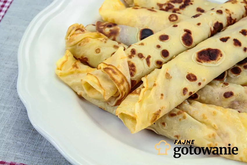 Naleśniki to zawsze świetny pomysł na szybki posiłek Naleśniki zwinięte w rulony podane na białym talerzu