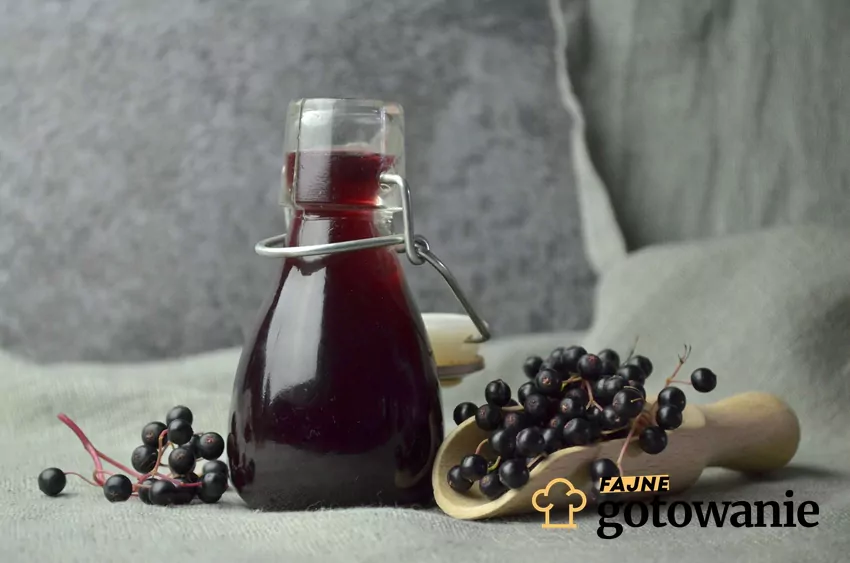 Buteleczka z sokiem wśród owoców czarnego bzu