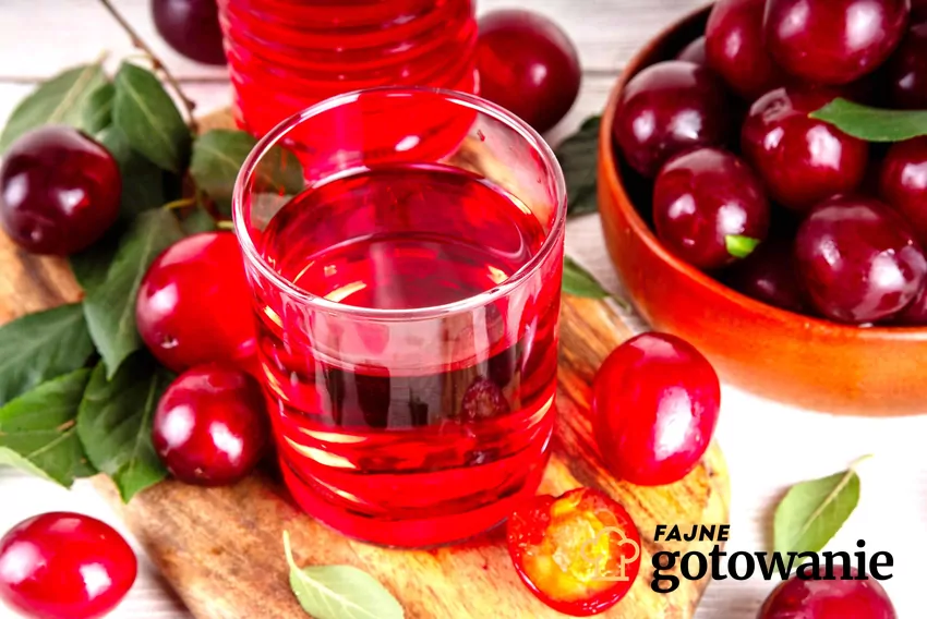 Kompot owocowy w szklance, obok leżą wiśnie