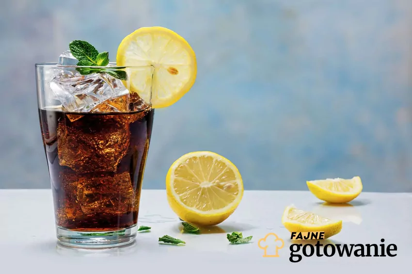 Cola w szklance, obok kawałki cytryny