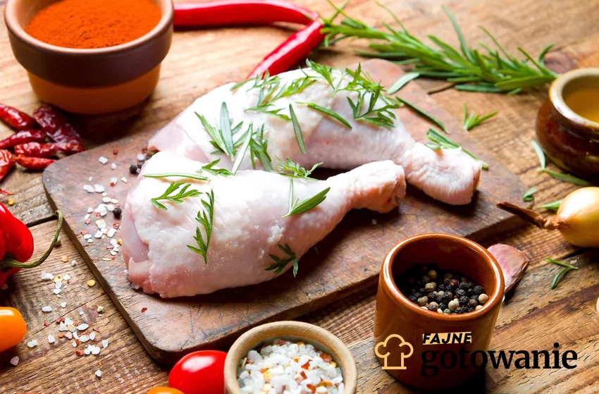 Odpowiednie zamarynowanie np. w solance może wpłynąć na soczystość mięsa Surowa noga z kurczaka ułożona na desce, wokół przyprawy