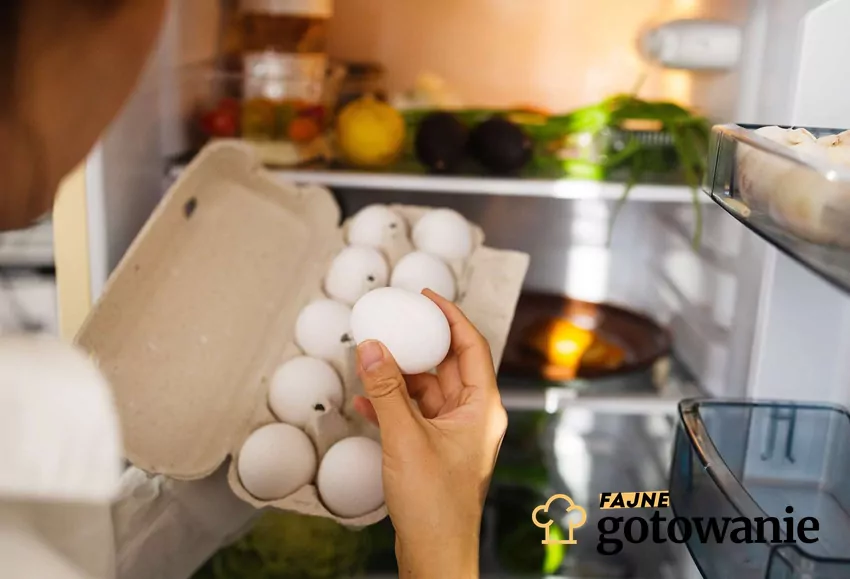 Choć w sklepach jajka są na półkach, to w domu warto trzymać je w lodówce Dłonie wyciągające jajka z lodówki