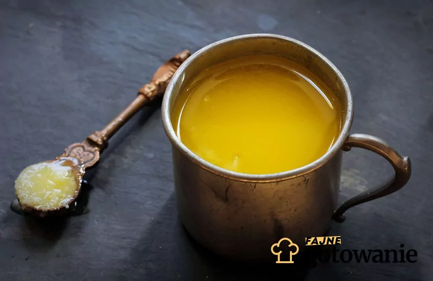 Masło ghee w metalowym kubku na ciemnym tle