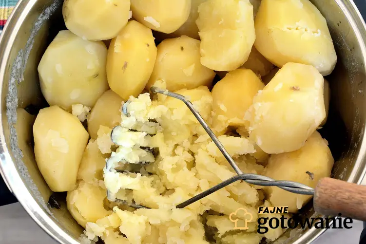 Ugotowane ziemniaki w garnku, tłuczone są przy pomocy tłuczka do ziemniaków