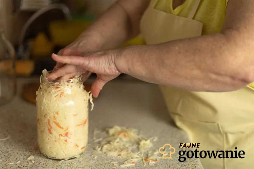 Kobieta robi kapustę kiszoną i wkłada ją do słoika oraz ugniata