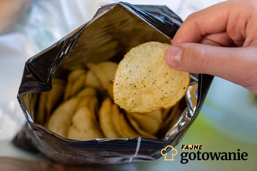 Trzymanie chipsa w dłoni nad otwartą paczką