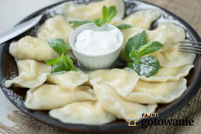 Ugotowane pierogi podane na talerzu ze śmietaną