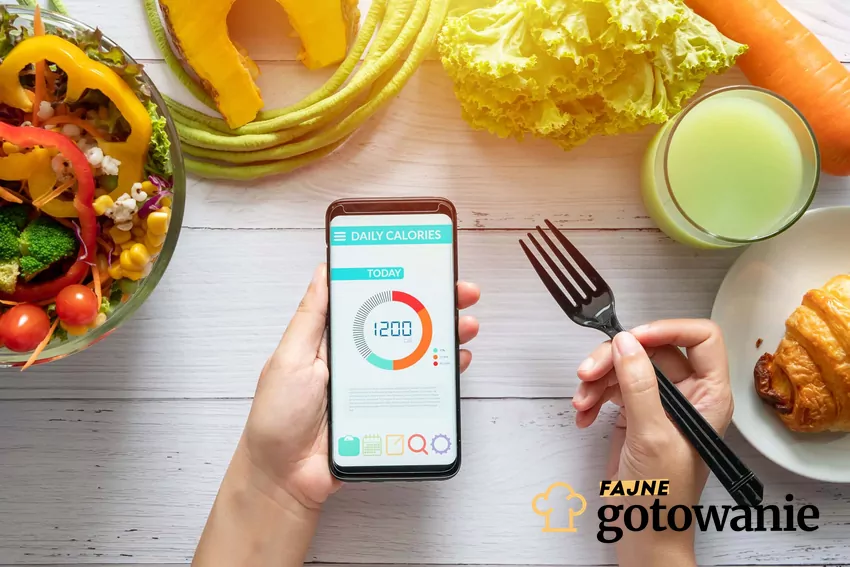 Dłoń trzyma telefon w ręku, naktórym jest grafika 1200 kcal, wokół stoi zdrowe jedzenie, zdrowe odżywianie przy diecie 1200 kcal, czego unikać w diecie niskokalorycznej