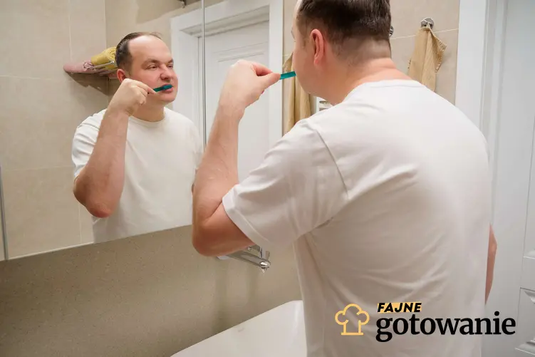 Mężczyzna z nadwagą myje zęby przed lustrem, a także jak mycie zębów wpływa na odchudzanie