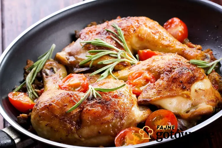 Smażony kurczak podany na patelni w towarzystwie pomidorów i świeżych ziół.