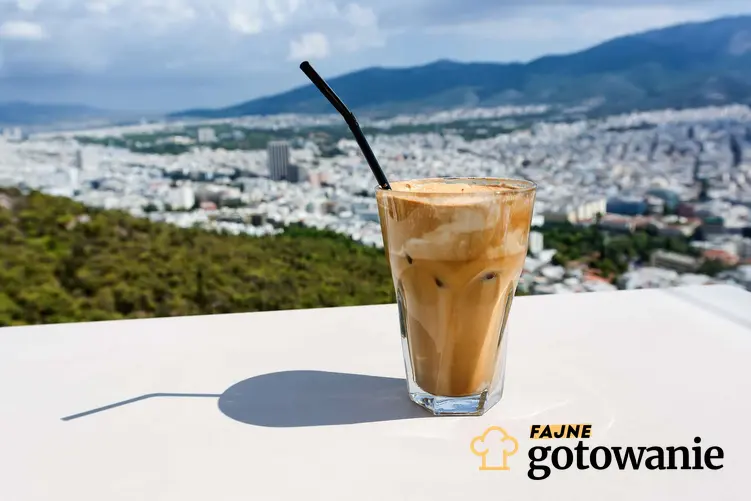Szklanka z kawą frappe ze słomką na tle miasta Ateny.