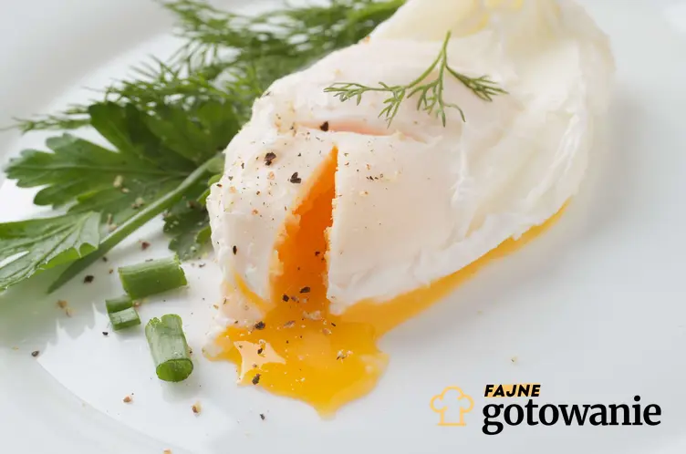 Jajka w mikrofali podane na małym białym talerzyku i udekorowane szczypiorkiem.
