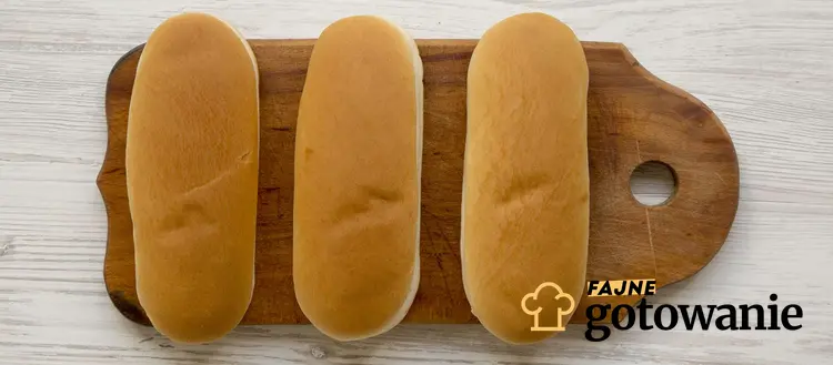 Bułki do hot-dogów podane są na drewnianej desce do krojenia.