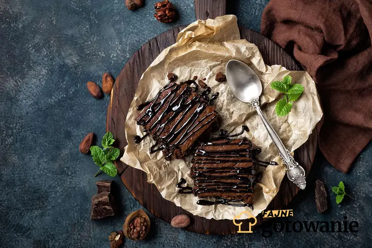 Wegańskie ciasto czekoladowe podane na drewnianej desce z czekoladą i kakao.