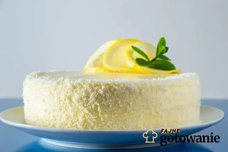Ciasto balowe ozdobione wiórkami kokosowymi i plastrami cytryny podane na białym talerzu.