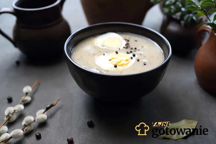 Zupa chrzanowa podana w ozdobnej miseczce i udekorowana jajkiem ugotowanym na twardo i ziarnami pieprzu.