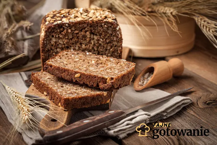 Chleb na maślance podany na beżowej ściereczce, obok nóż i źdźbła zbóż.