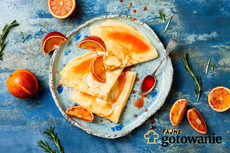 Crepe suzette podane na ozdobnym talerzu z dodatkiem pomarańczy.