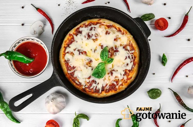 Pizza z patelni podana na patelni żeliwnej, z sosem pomidorowym, bazylią i papryczkami chili.