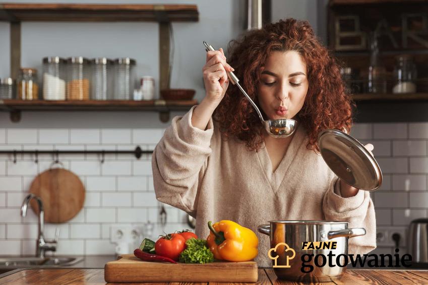 Kobieta w kuchni próbuje zupę prosto z chochli, kobieta stosuje płynną dietę, jakie zupy jeść przy płynnej diecie, czego unikać podczas stosowania diety plynnej