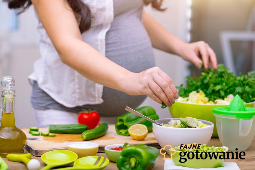 Kobieta w ciąży przygotowująca sobie sałatkę, a także dieta w ciąży i jej charakterystyka, produkty i dania