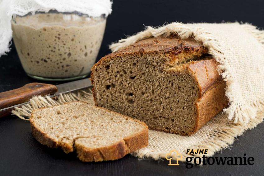 Chleb pszenny na zakwasie przykryty ściereczką z zakwasem w tle.