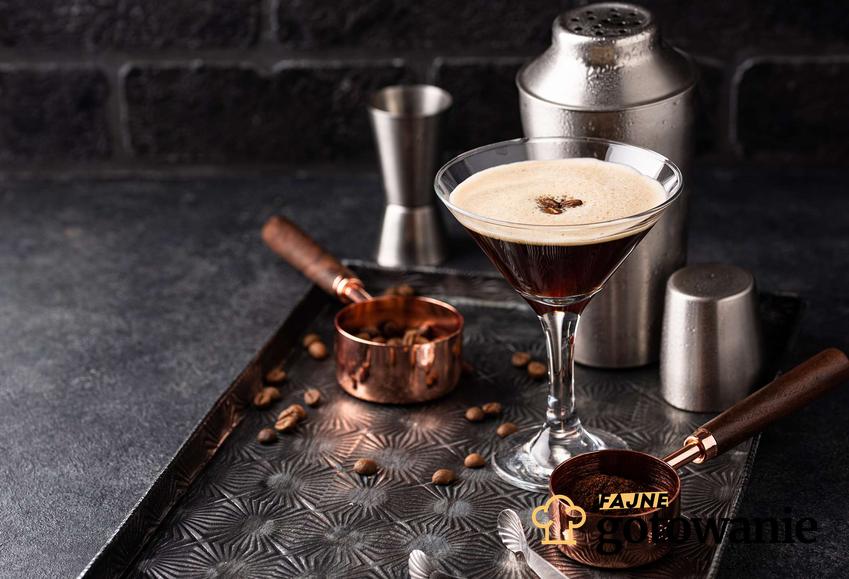 Espresso martini podane w kieliszku, który stoi na metalowej tacy.