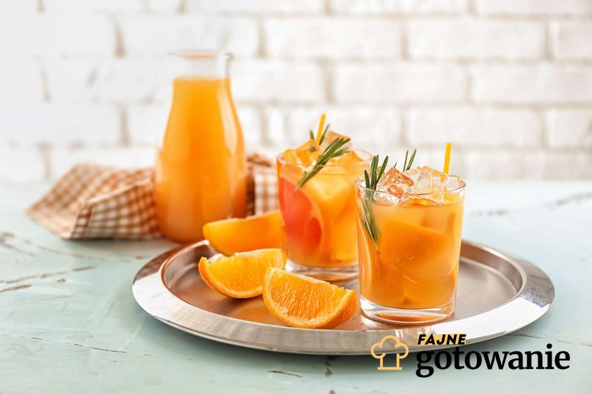 Koktajl z pomarańczy z dodatkiem lodu i rozmarynem podany w szklankach.