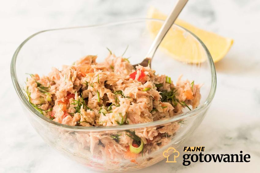 Sałatka z tuńczykiem i warzywami, podana w przezroczystej misce.