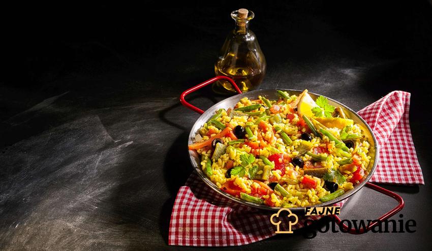 Paella wegetariańska podana na patelni i udekorowana warzywami.