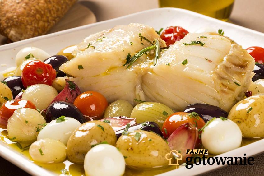 Bacalhau podana z warzywami na białym talerzu.