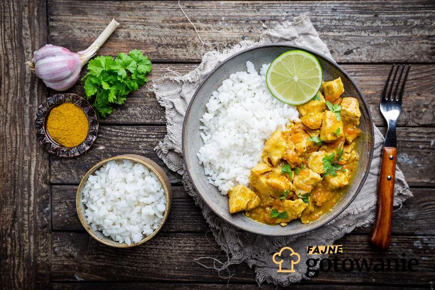 Kurczak po indyjsku curry podany na talerzu z ryżem i limonką.