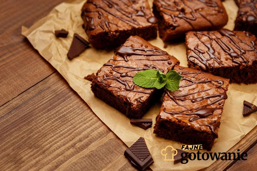 Brownie Thermomix pokrojone na kawałki, ułożone na papierze i polane czekoladą.