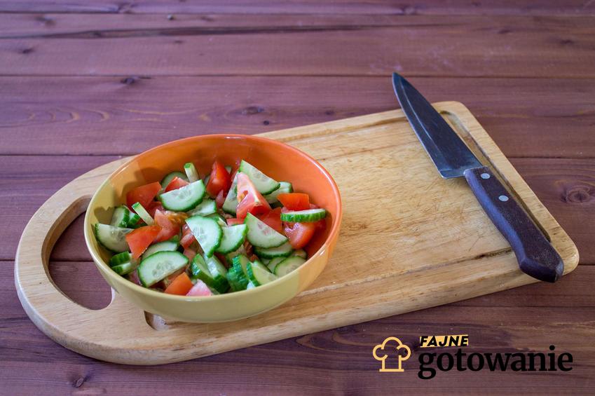 Sałatka z pomidorami i ogórkiem podana w drewnianej misce.