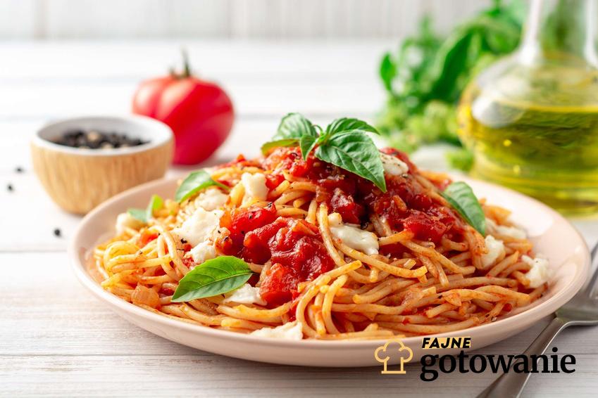 Spaghetti z pomidorami z puszki podane z bazylią.