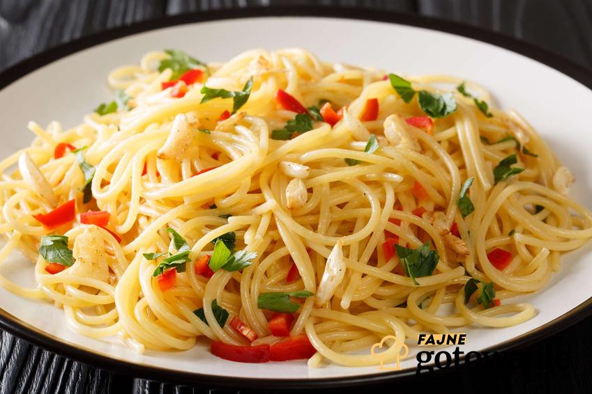 Spaghetti aglio olio podane na białym talerzu.
