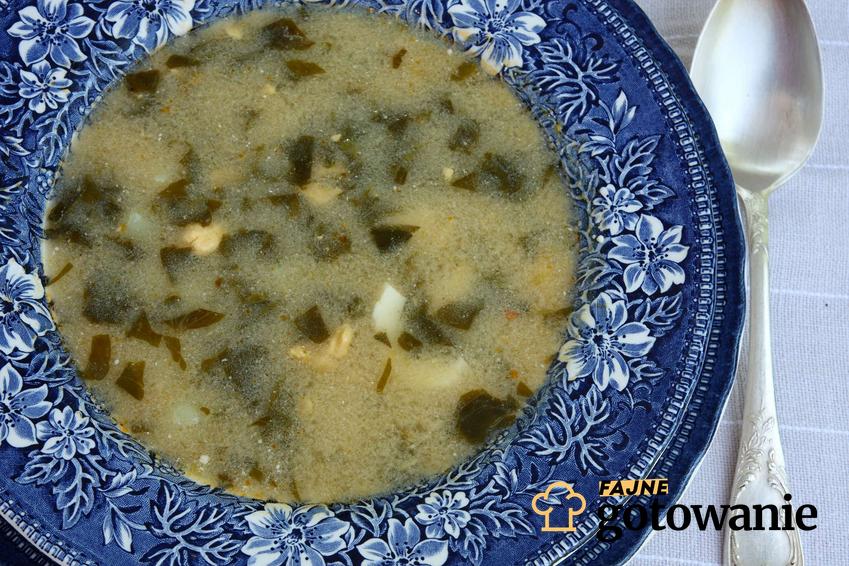 Zupa szczawiowa tradycyjna podane w niebieskim, głębokim talerzu.