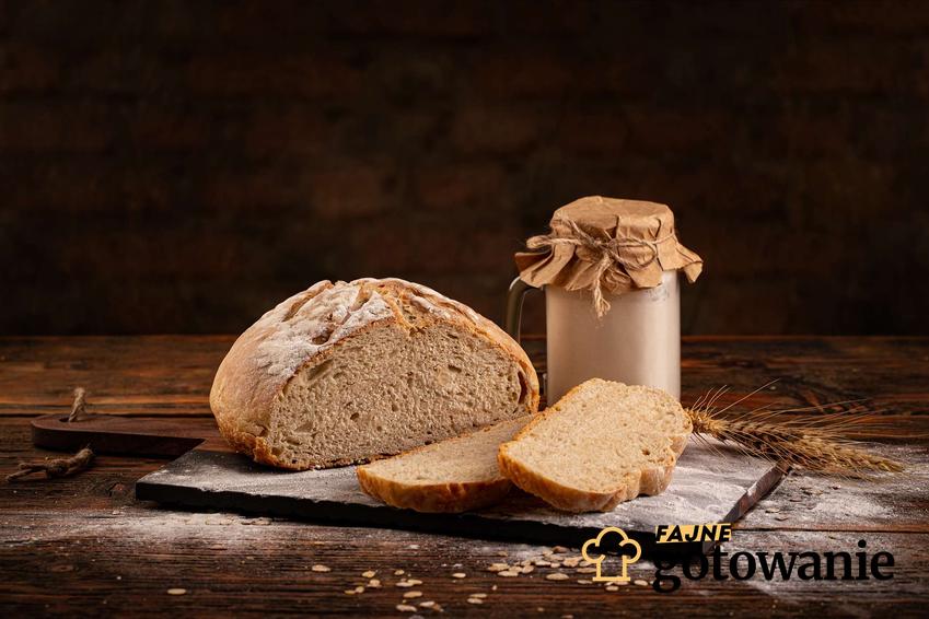 Zakwas żytni na chleb podany w słoiku. Obok niego leży upieczony chleb.