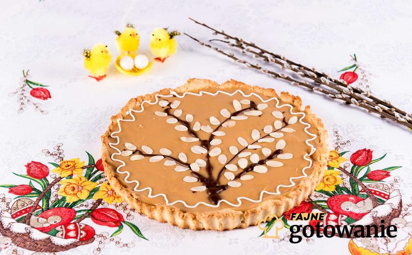 Mazurek ciasto ułożone na świątecznym obrusie wielkanocnym.